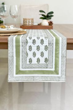 a table with a green and white placemat on it, next to some wine glasses