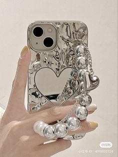 a woman holding up her phone case with pearls on it