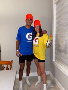 a man and woman wearing orange hats pose for a photo in front of a white wall