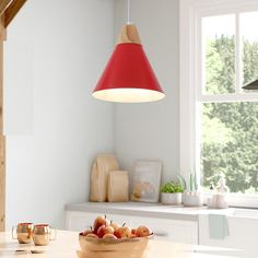 a bowl of fruit sitting on top of a wooden table next to a light fixture