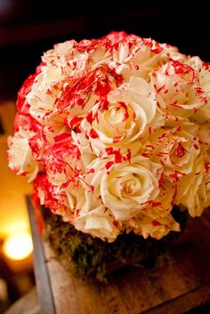 a bouquet of white and red flowers sitting on top of a wooden table