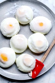 four fried eggs on a plate with a red spatula and wooden spoon next to them