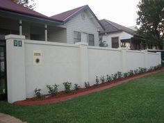 a white house with a fence in front of it and grass on the ground next to it