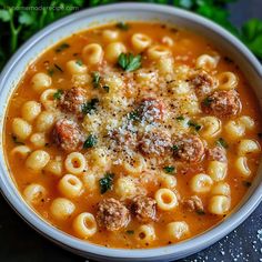 a bowl of pasta soup with meatballs and parmesan cheese on the top