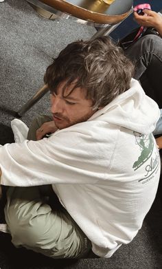 a man sitting on the floor with his legs crossed and looking down at something in front of him