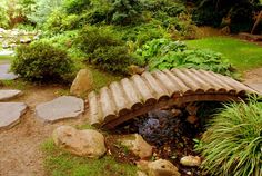 a small wooden bridge over a stream in a garden