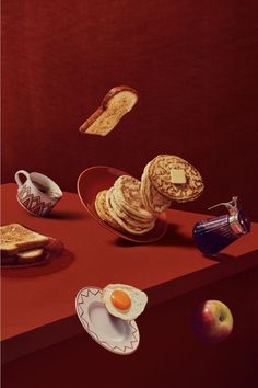 a red table topped with plates and bowls filled with different types of breakfast foods on top of it