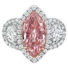 a fancy pink diamond ring with three pear shaped diamonds in the center and an oval cut on