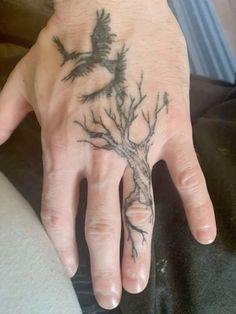 a person's hand with a tree tattoo on it and a bird flying above the tree