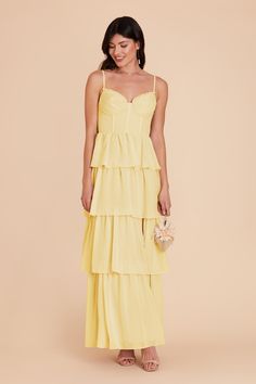 a woman wearing a yellow dress with spaghetti straps and tiered ruffles on the bottom