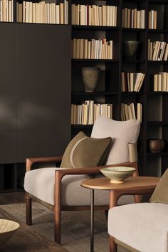 two chairs and a table in front of a bookcase with books on the shelves