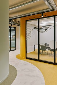 an office building with glass walls and yellow flooring is seen from the entrance to the conference room