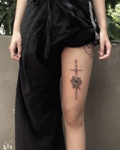 a person standing next to a wall with a cross tattoo on their thigh and leg