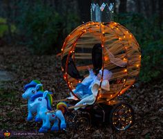 a small toy carriage with lights in the shape of a pumpkin and two blue ponies