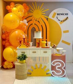 an orange and yellow birthday party with balloons on the wall, cake table and decorations