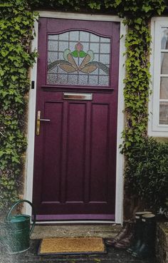 a purple front door with green ivy growing on the side of it and a window