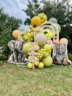 an outdoor display with balloons, animals and other items on the grass in front of trees