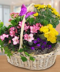 a basket filled with lots of flowers and a butterfly sitting on top of the flower