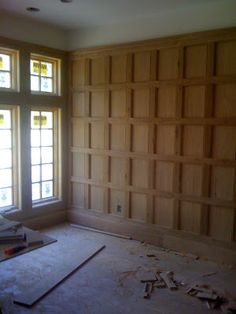 an empty room with wood paneling in the middle and windows on the far side