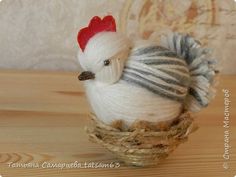 a small white and gray chicken sitting in a nest on a wooden table next to a wall