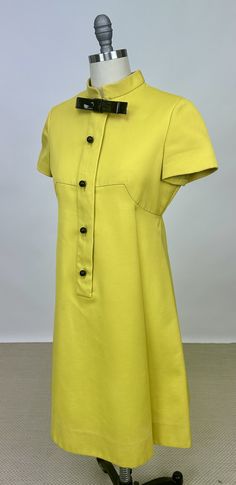 Vintage 1960s Designer Teal Traina New York Mod Dress Yellow Acetate Short Sleeve with Plastic Bowtie Black Buttons. Here we have a 1960s Teal Traina mod dress. It is a yellow/lime green color and made from a synthetic acetate material. The interior is lined with a silky acetate. It features a center front zipper with snap buttons overtop that look like real buttons. It is shortsleeved and falls to the knees. There is a large box please on the front and back of the dress at the waistline. This piece is in fair vintage condition, however there are a few areas of discoloration. Most notably is the orange tinge behind the the plastic bow tie. There are a few other much fainter stains down the front. Please view all photos prior to purchasing, this item is sold as is and has been priced accord Yellow Retro Formal Dress, Yellow Retro Dress For Formal Occasions, 1960s Dresses, Yellow Lime, Dress Yellow, Mod Dress, Black Button, Vintage 1960s, Dress Clothes For Women