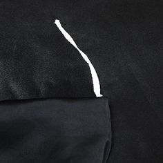 the back side of a black jacket with white stitching