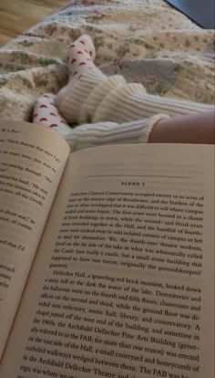 an open book sitting on top of a bed next to a person laying in bed