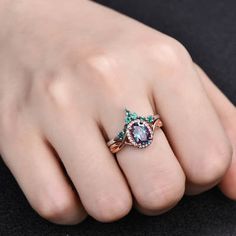 a woman's hand wearing a ring with an oval shaped stone surrounded by diamonds