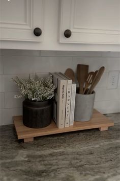 a kitchen counter with some utensils in a pot and two books on it