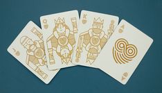 four playing cards with gold foil designs on red paper, sitting in front of a pink background