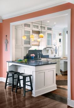 an open kitchen with two stools in front of the island