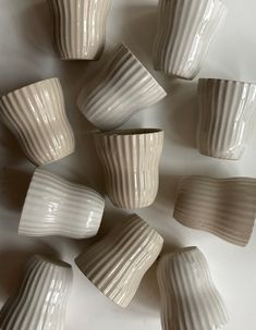 several white cups are arranged in a pattern on the table top, one is empty