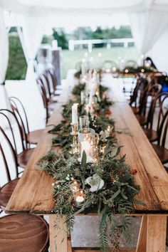 a long wooden table topped with greenery and candles