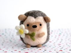 a hand holding a tiny stuffed animal with a flower in it's mouth,