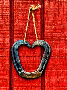 a heart shaped door hanger hanging on a red wooden door with rope attached to it