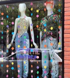 two mannequins in a window with multicolored confetti on them