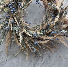 a wreath with blue berries hanging on the side of a stone wall in front of a person's hand