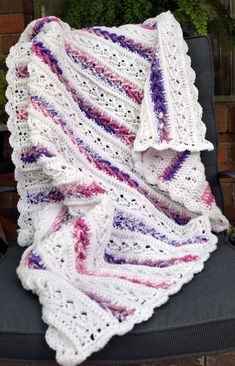 a white crocheted blanket sitting on top of a chair next to a potted plant