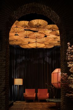 an archway with chairs and umbrellas hanging from it's ceiling in a dark room