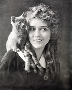 an old black and white photo of a woman with a cat on her shoulder,