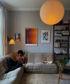 a man sitting on top of a couch in a living room next to a window