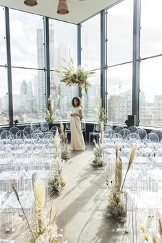 a woman standing in an empty room with lots of clear chairs and flowers on the floor