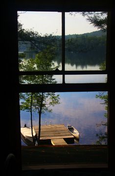 the view from an open window looking out at a lake and dock in the distance