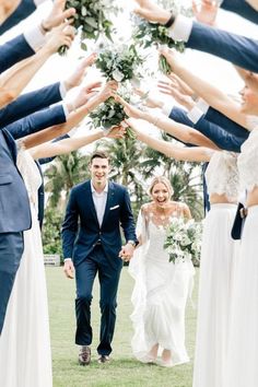 a bride and groom walking through a group of people with their hands in the air