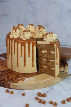 a cake with white frosting and caramel drizzled on top sitting on a cutting board