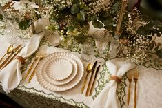 the table is set with gold and white plates, napkins, and silverware