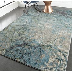 an area rug with a blue and green design on the floor next to a chair