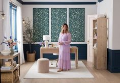 a woman in a pink dress standing next to a desk