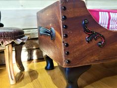 a wooden chair with metal hardware and knobs on the legs, sitting next to a footstool