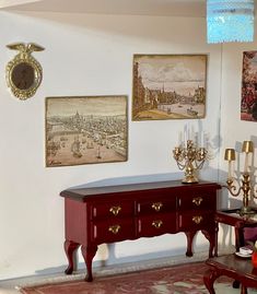 a red table with two vases sitting on top of it next to a mirror